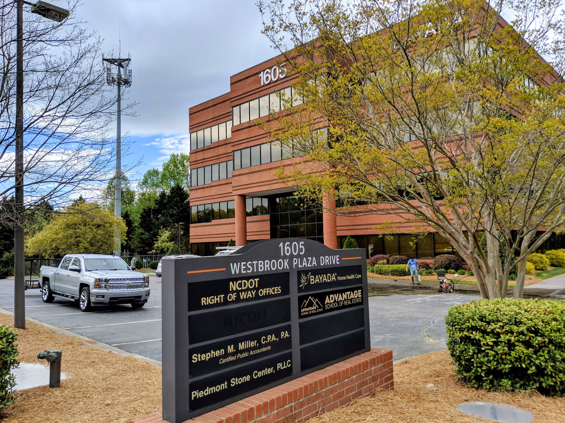Brick office building exterior with Bayada Home Health sign and a large information board in foreground.