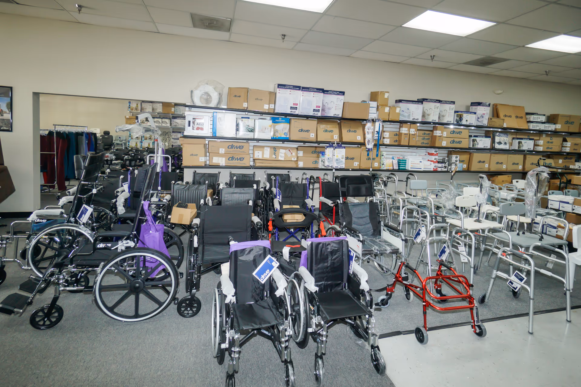 A cluttered indoor storage room filled with wheelchairs, walkers, and boxed supplies.