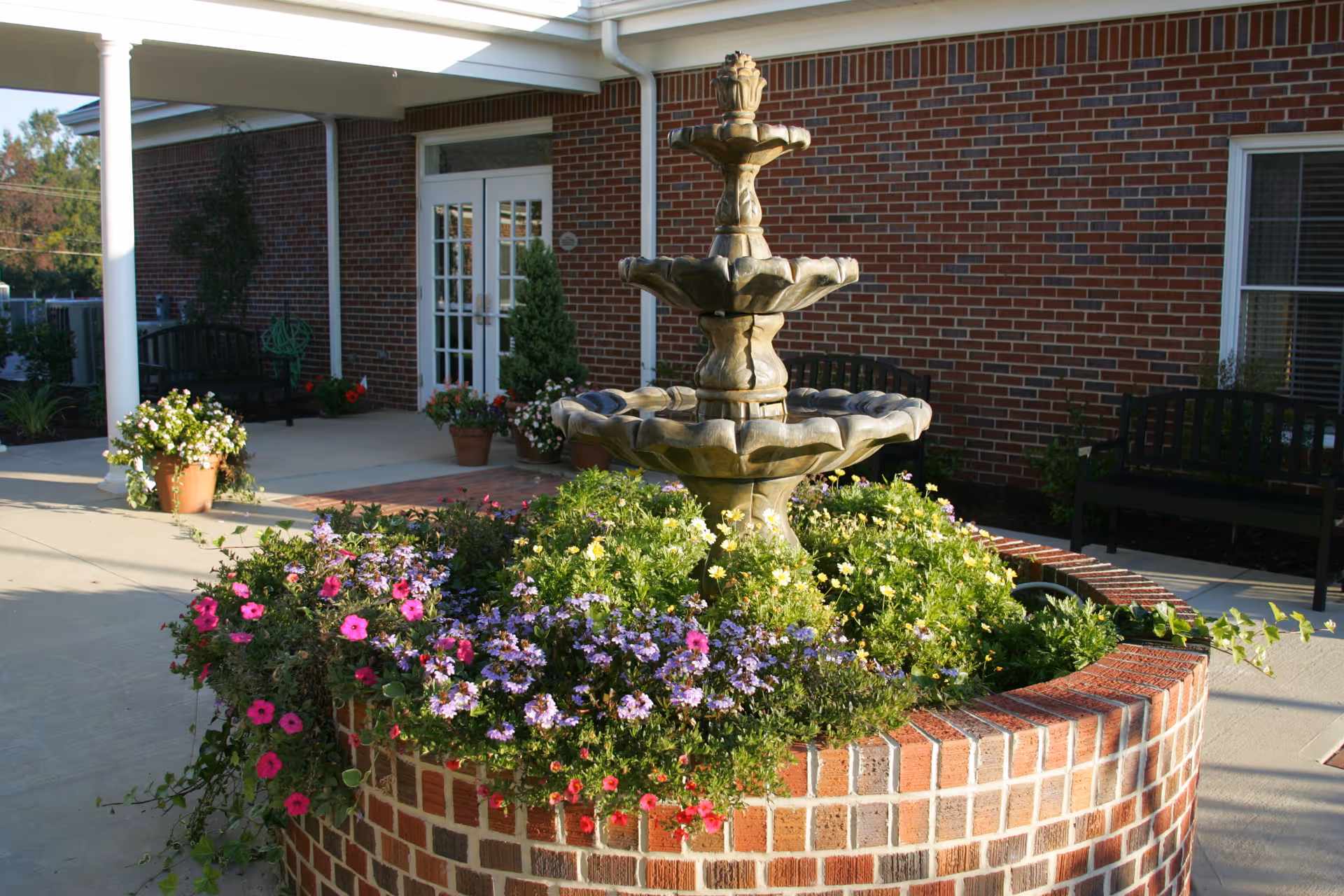 Exterior view of a brick building with a circular planter and fountain.