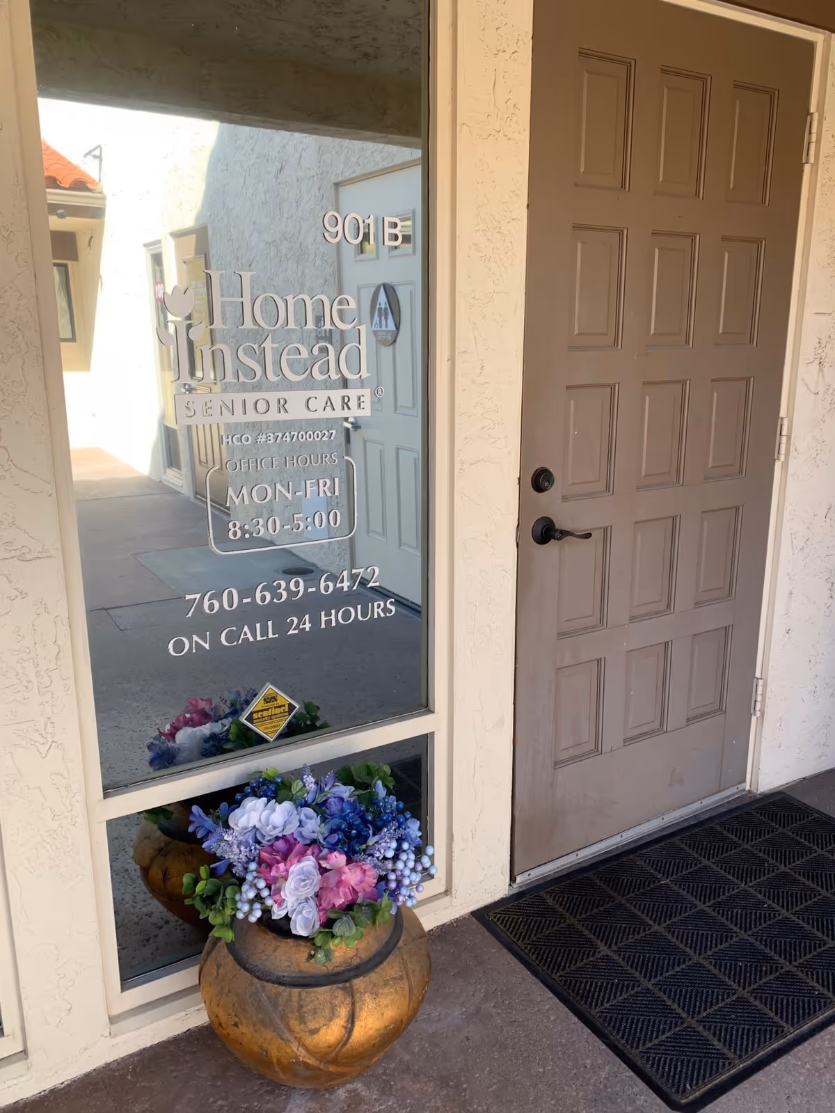 Front entrance of Home Instead Senior Care with glass door, address 901B, and flower pots.