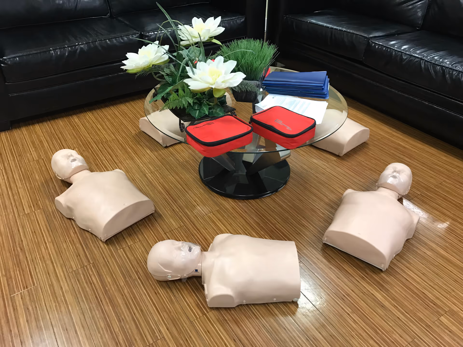 CPR training mannequins arranged around a glass coffee table in a lounge area.