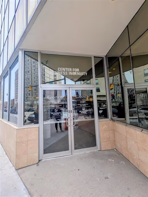 Glass storefront entrance with Center for Business Ingenuity signage and reflections.