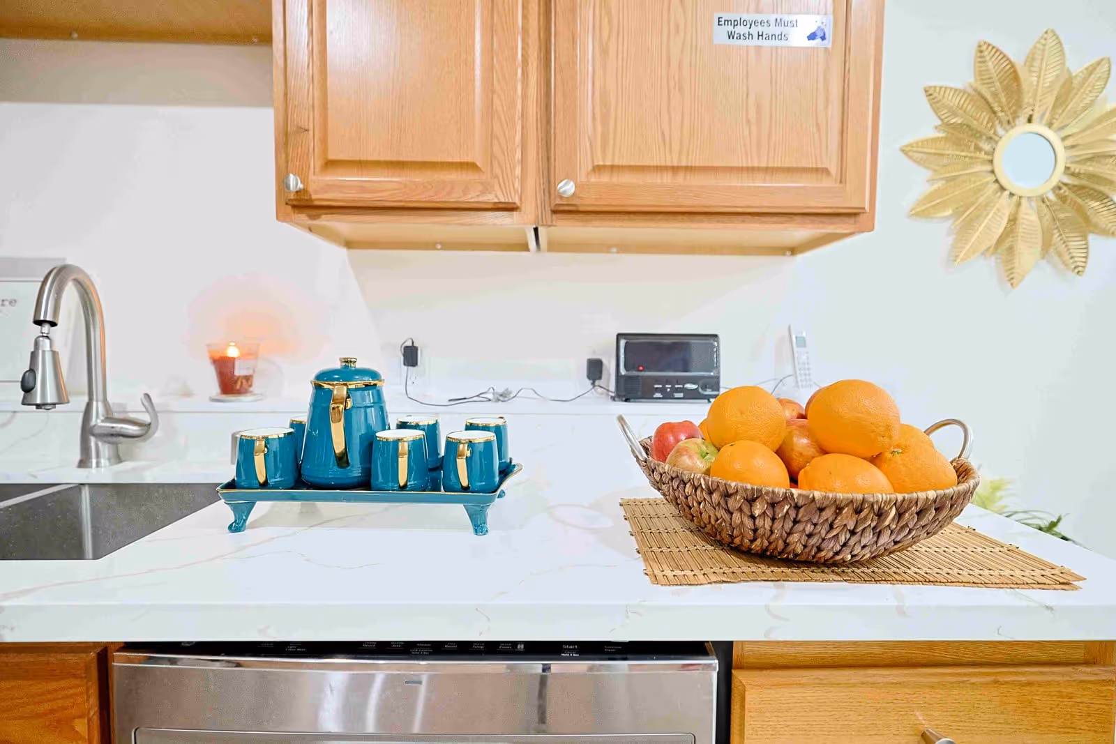 A clean kitchen counter with turquoise tea set and a fruit basket.
