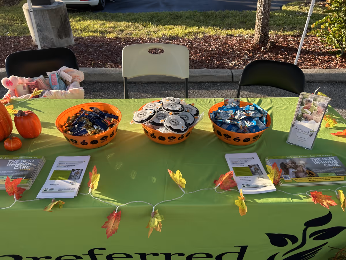 Outdoor event table with candy baskets, brochures, and autumn leaves.