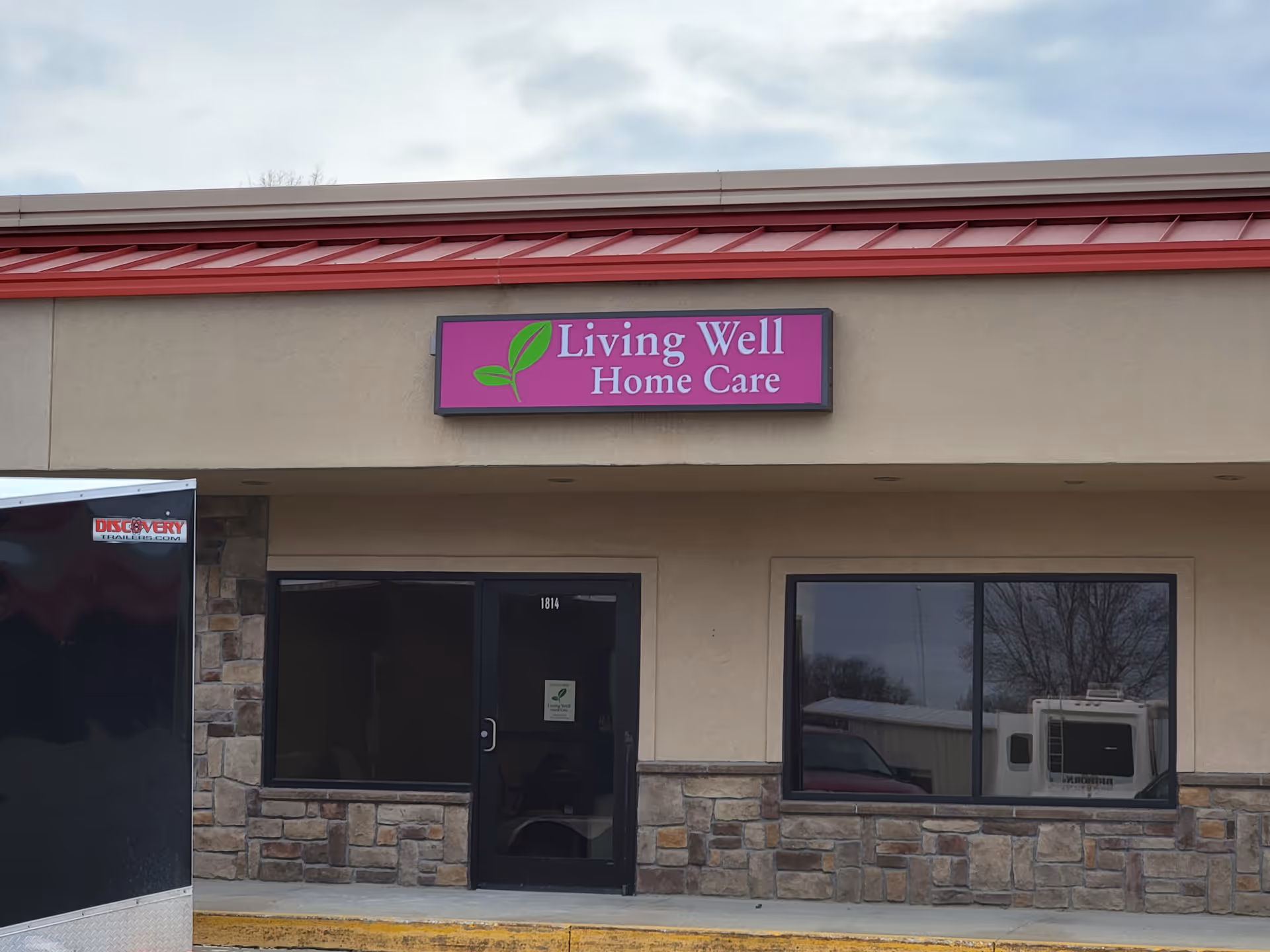 Front view of a beige building with a purple Living Well Home Care sign.