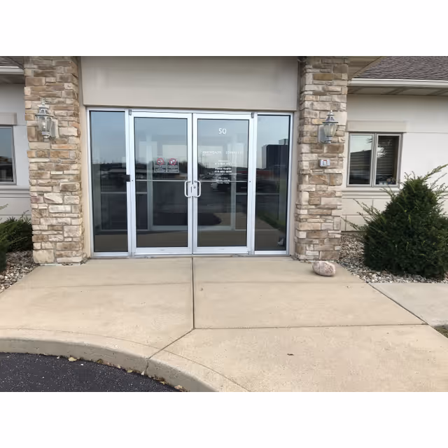 Front entrance with double glass doors framed by stone pillars at OhioHealth Hospice with Compassus.