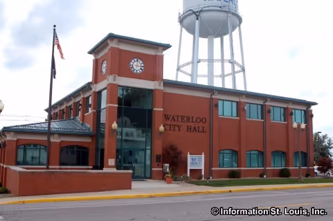 Front exterior of Waterloo City Hall, a red brick building with clock tower and water tower.
