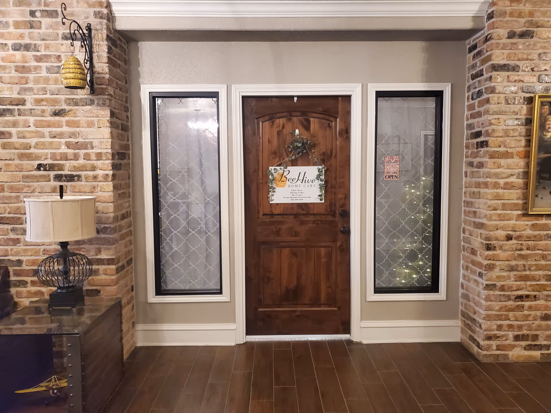 Wood door flanked by glass panels in brick-walled interior entryway.