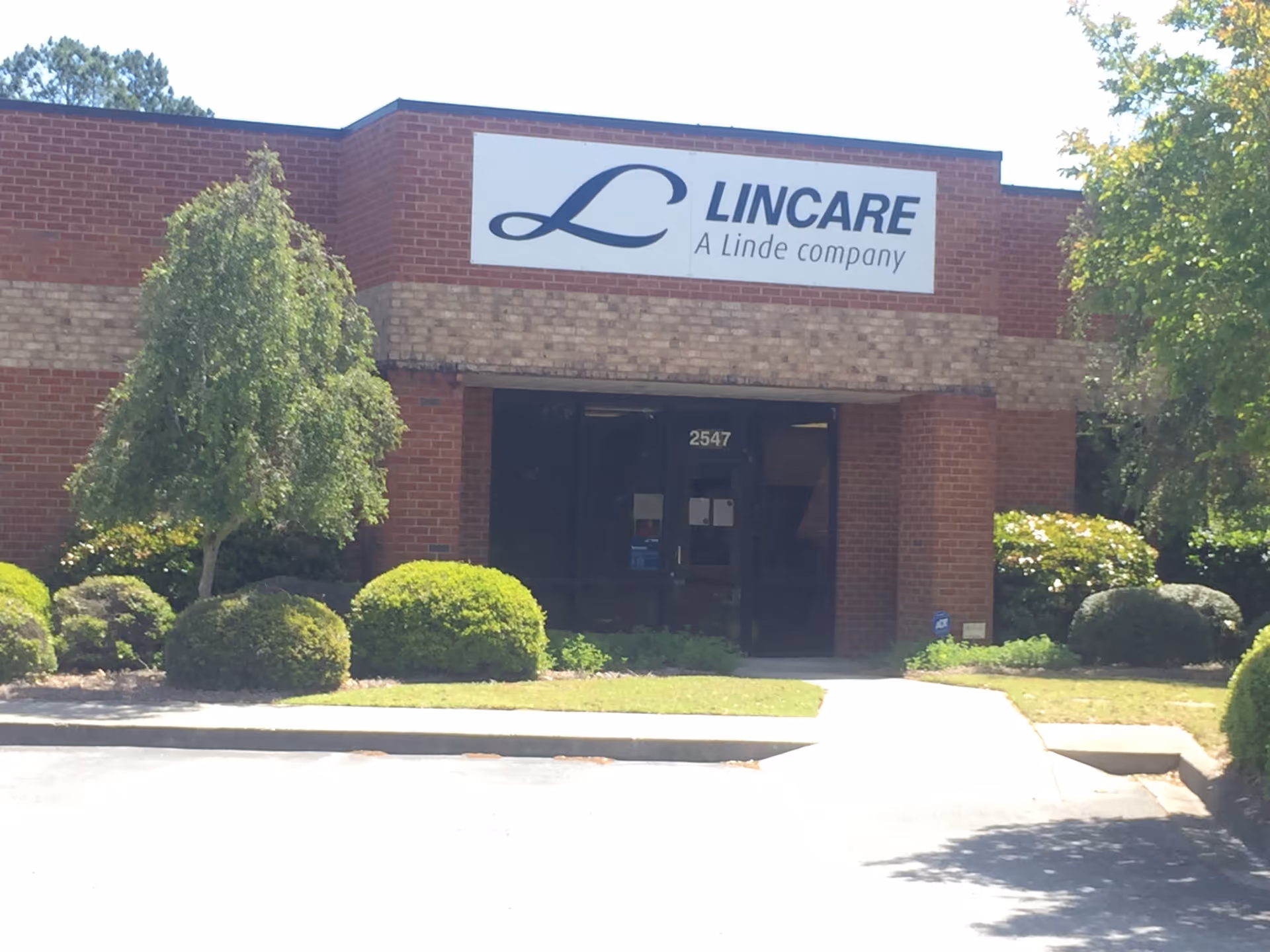 A Lincare facility front with sign, brick exterior, and trimmed shrubs.