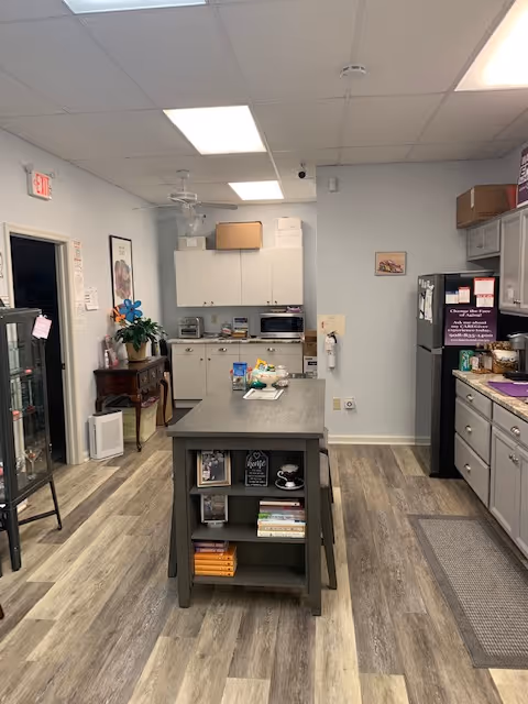 A small institutional kitchen with an island, cabinets, and appliances in a senior facility.