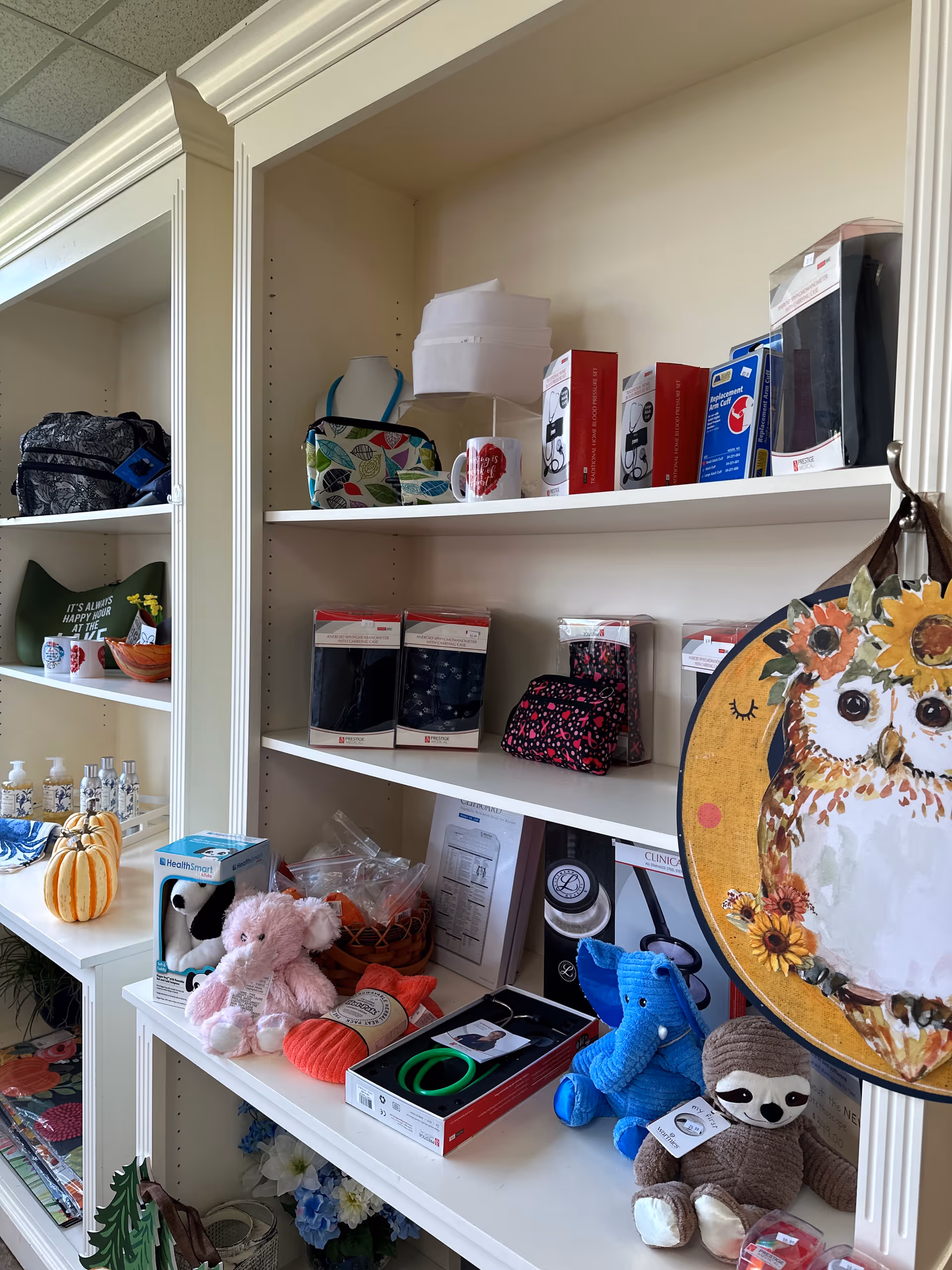 Bright room with white shelves displaying gifts, toys, and medical items.