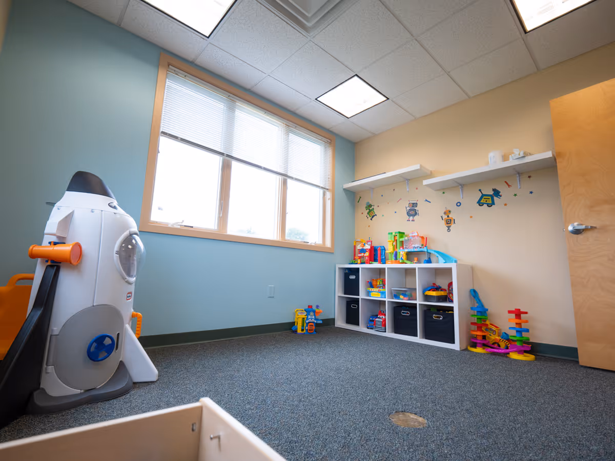 Bright playroom with toy shelves and a large window inside a senior living facility.