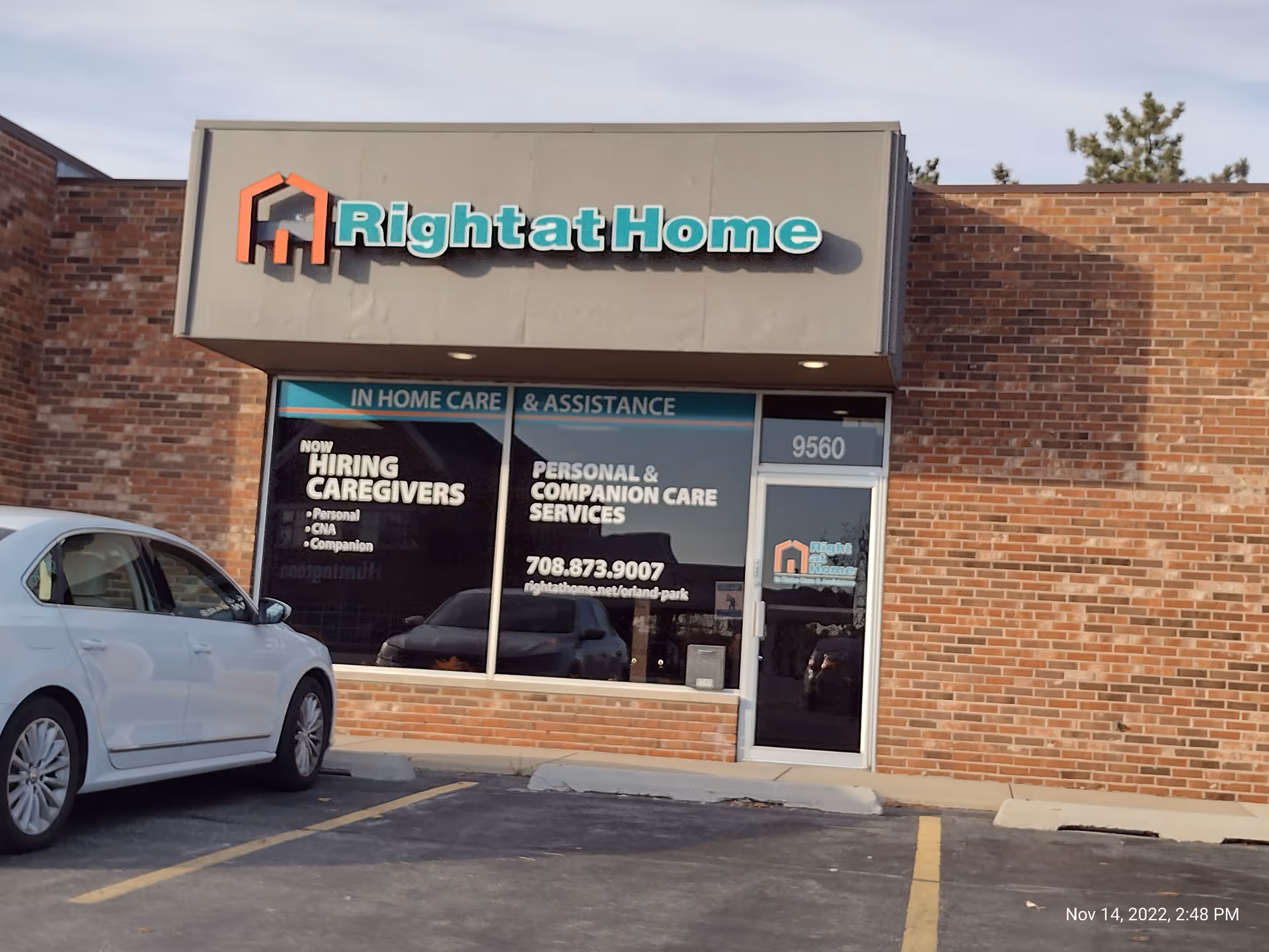 Exterior view of a Right at Home senior care storefront with brick facade and parked car.