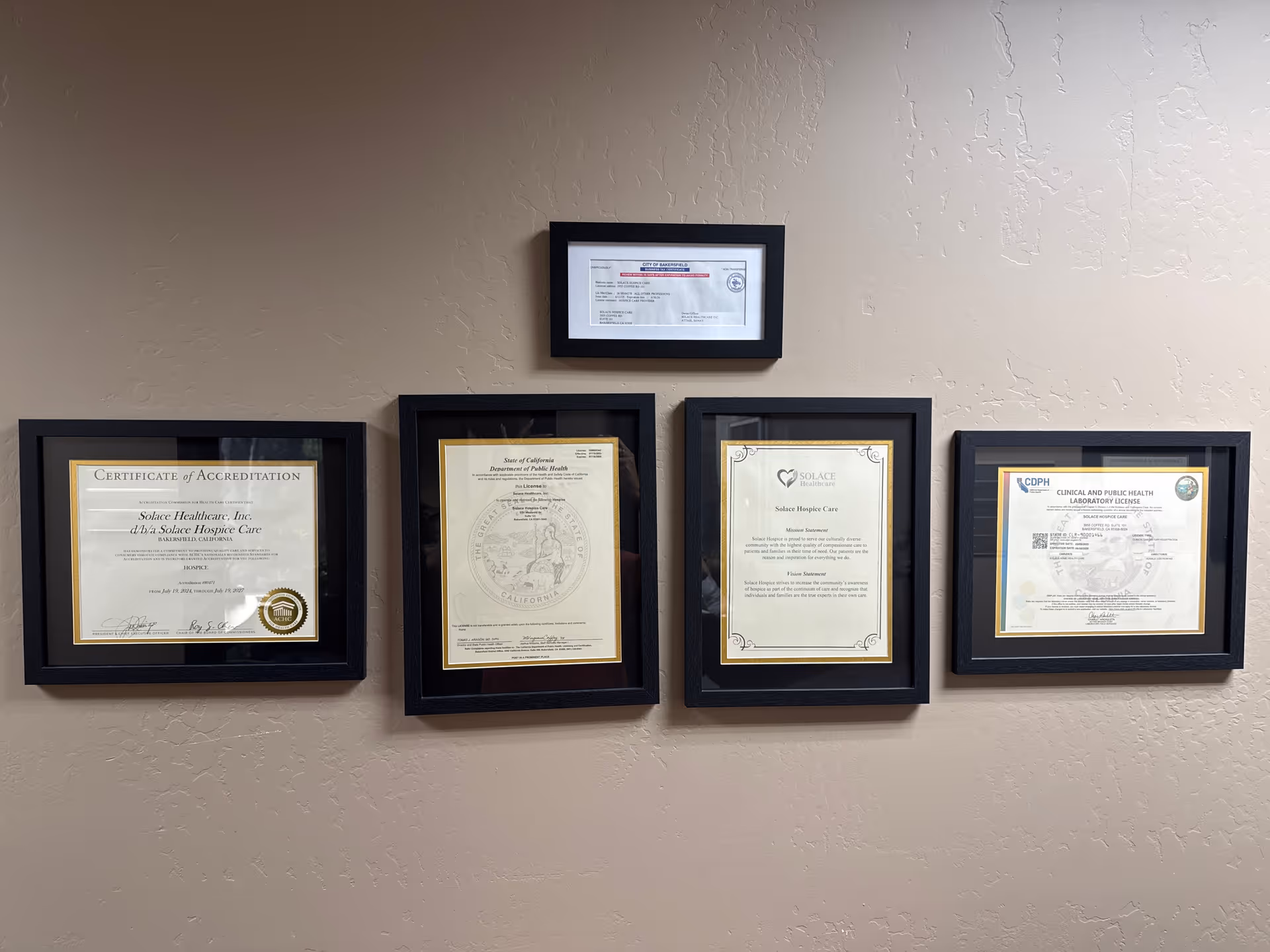 Beige wall with five framed accreditation and license certificates.