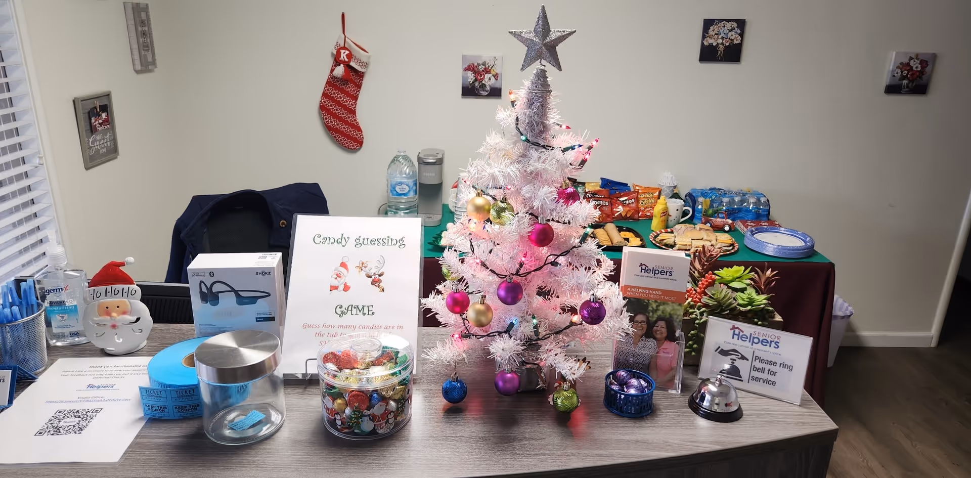 Reception desk display with a small Christmas tree, candy jars, and Senior Helpers materials.