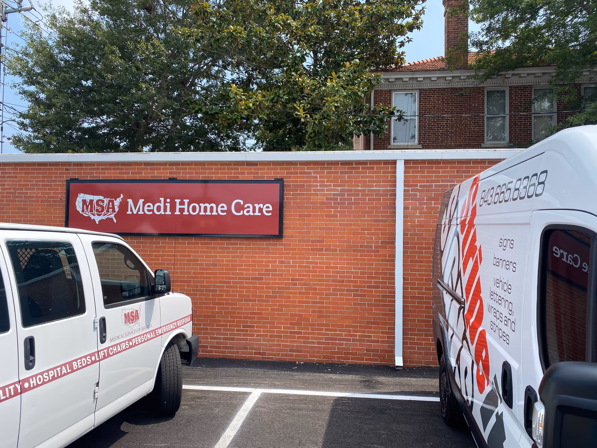 Brick building exterior with Medi Home Care sign and two service vans parked outside