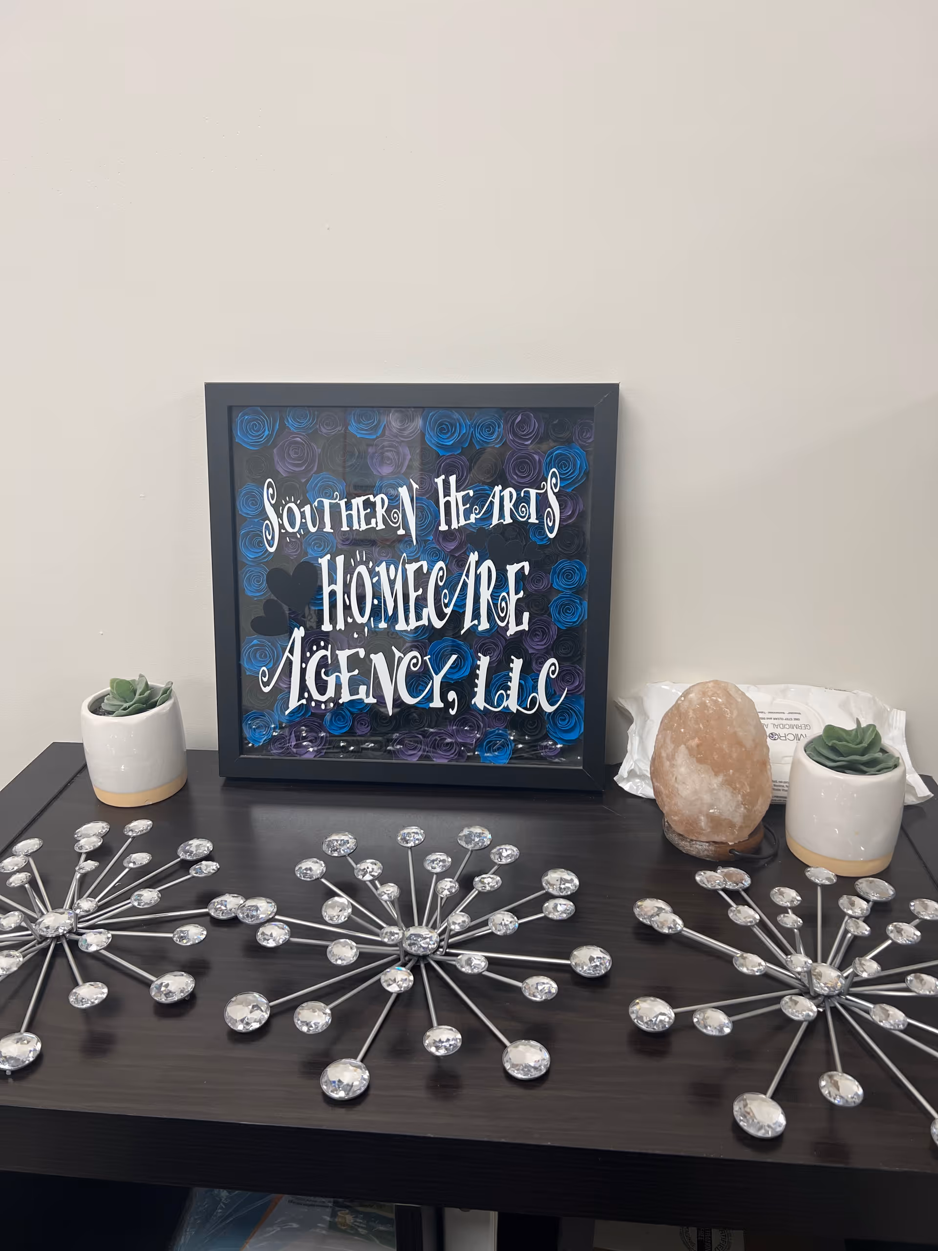 Framed sign 'Southern Hearts Homecare Agency LLC' sits on a dark desk.