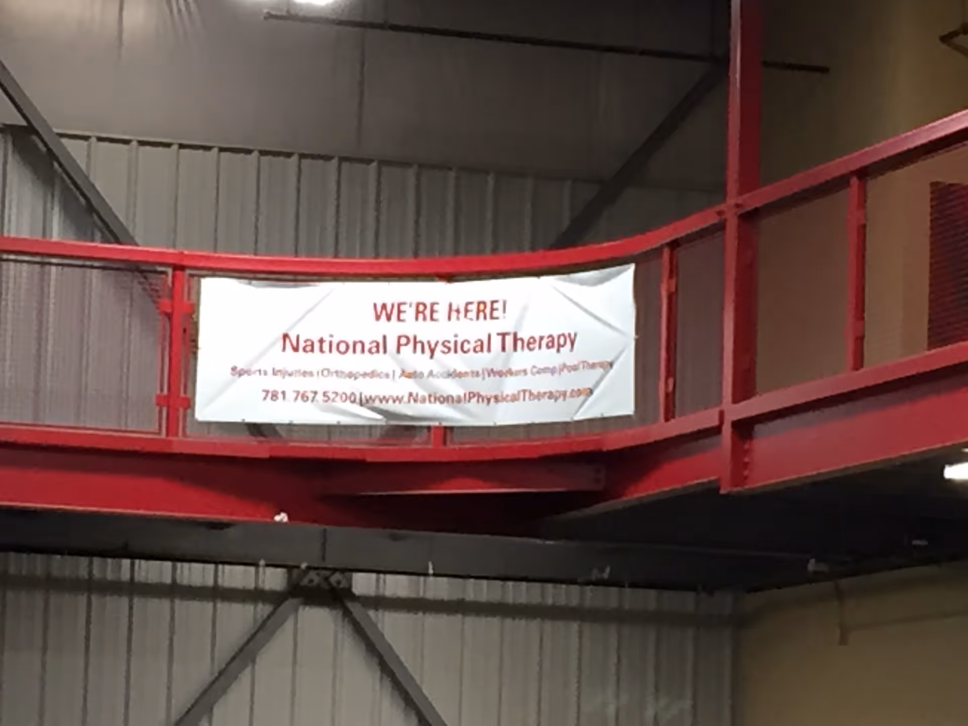 Industrial interior with red walkway railing and a banner for National Physical Therapy