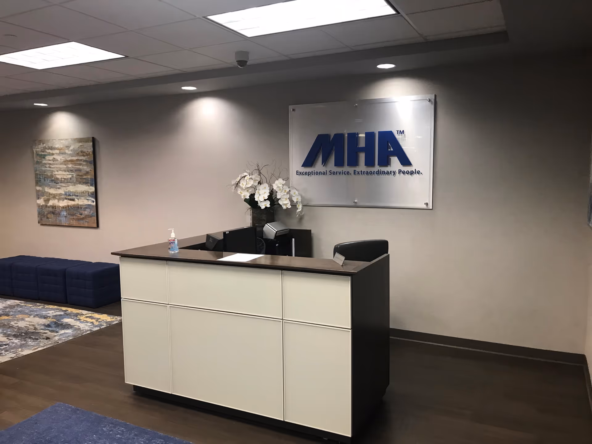 Reception desk in a modern lobby with an MHA sign, seating, and wall art.