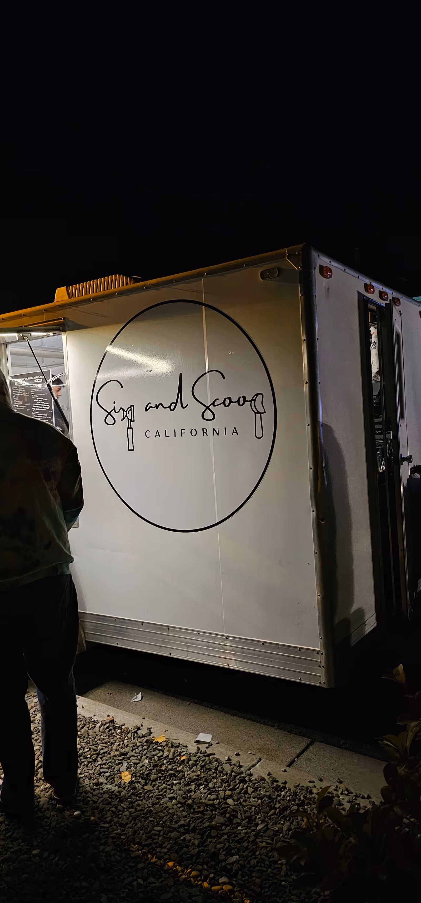 Night exterior shot of a white food trailer with circular California logo.