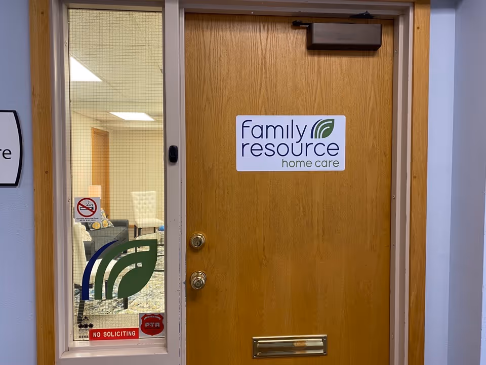 Wooden door with Family Resource Home Care sign next to a glass panel showing interior room.