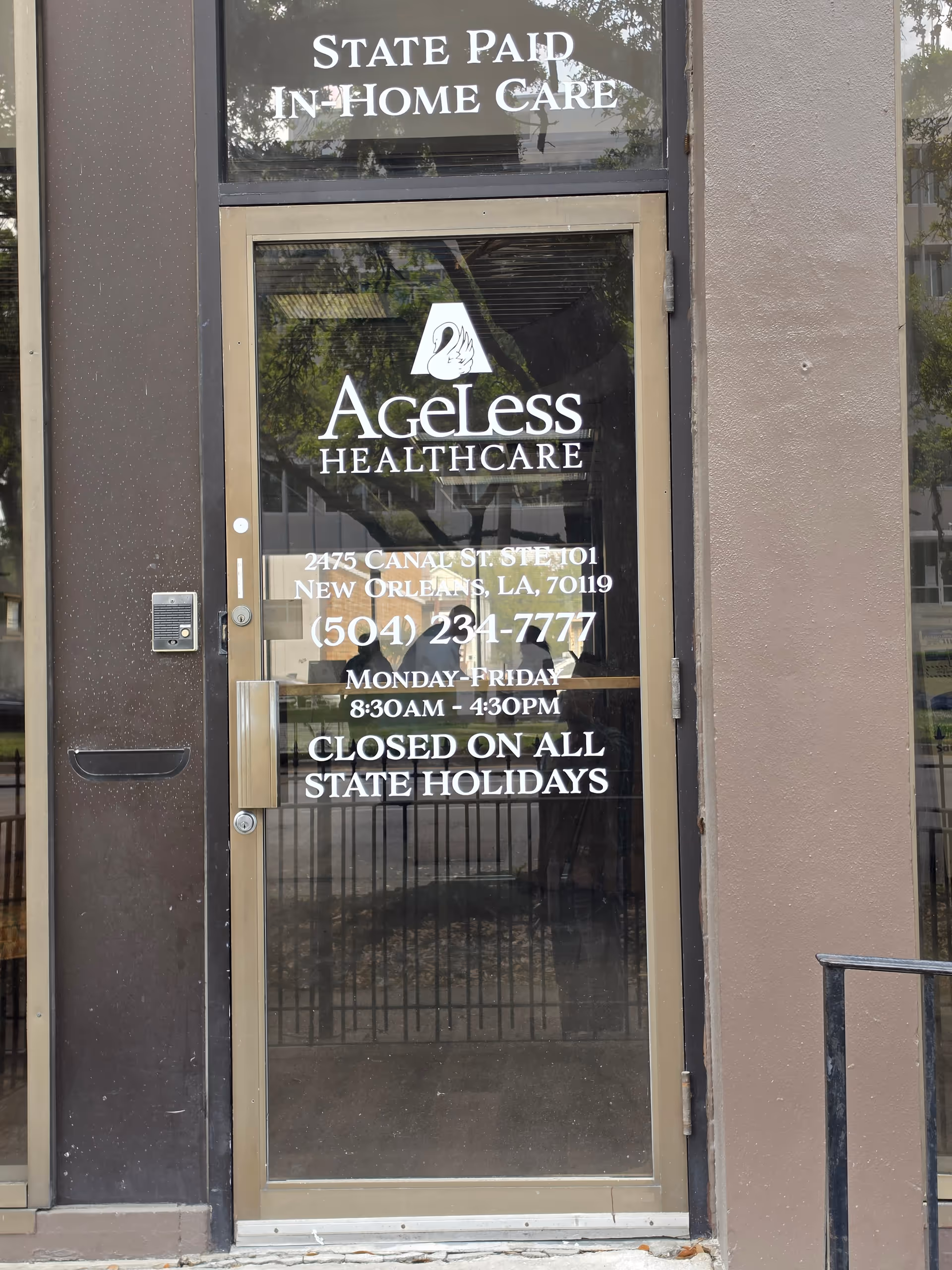 Exterior glass door of Ageless Healthcare entrance displaying logo, contact info, and hours.