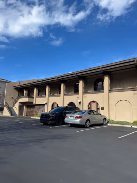Exterior view of a HomeWell Care Services building with parked cars and blue sky.