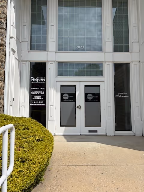 Exterior entrance of Senior Helpers of Bel Air with glass doors and surrounding landscaping.