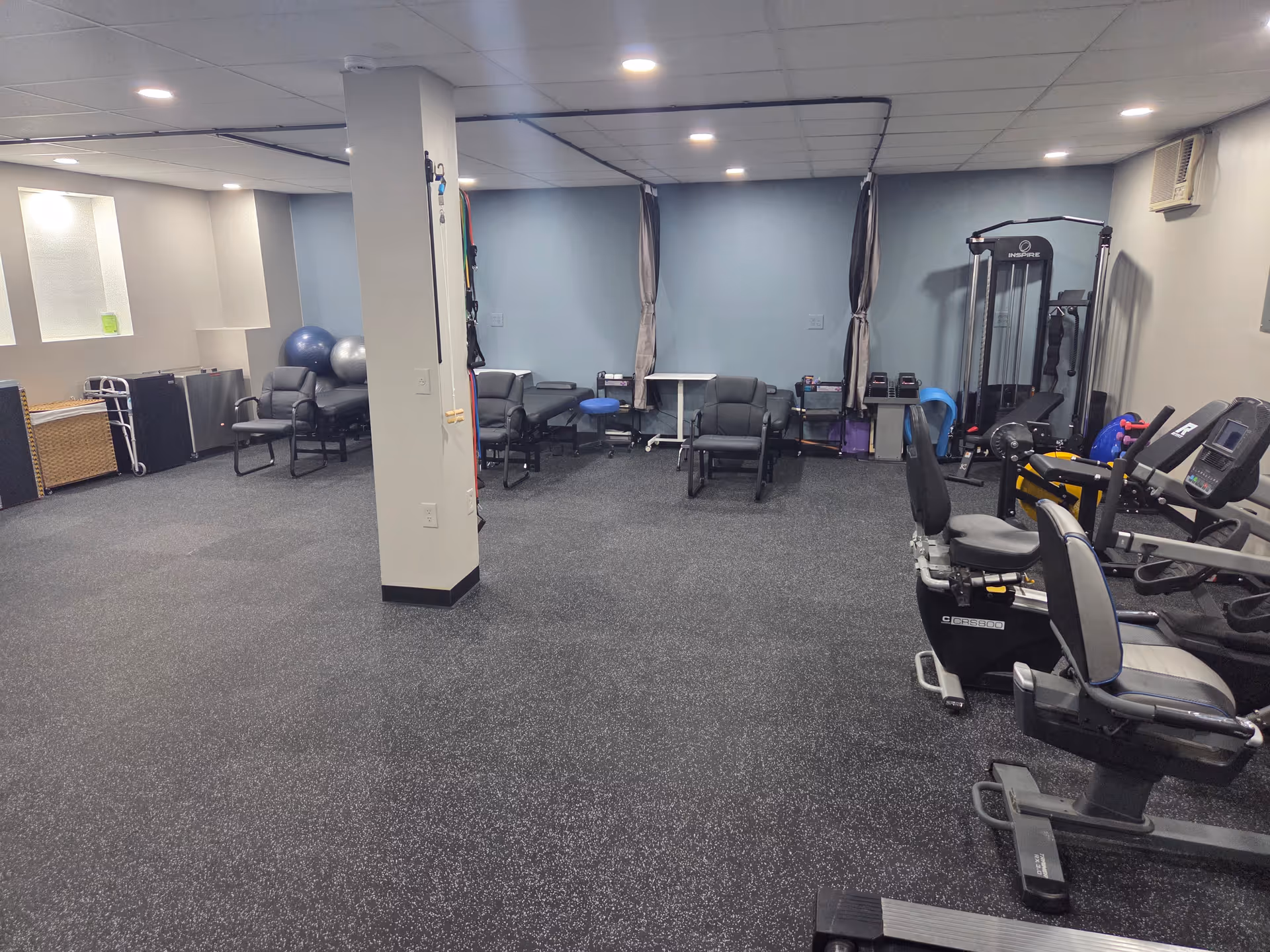 Interior of a senior fitness room with cardio machines, weights, and seating.