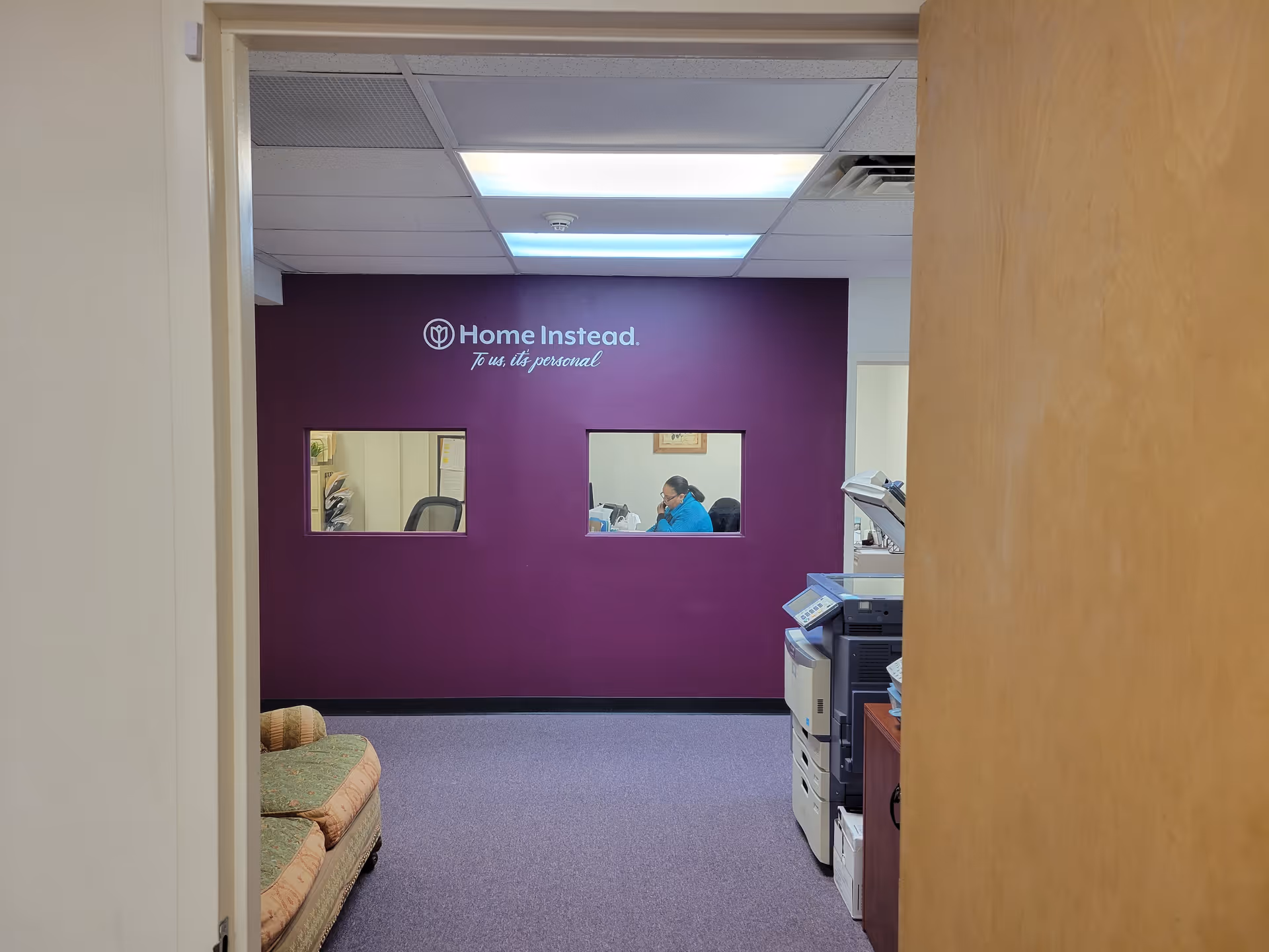Home Instead reception area with purple wall and two windows.