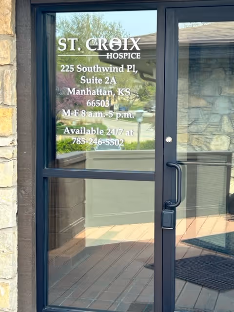 Glass door with St. Croix Hospice signage and address listing at building entrance.