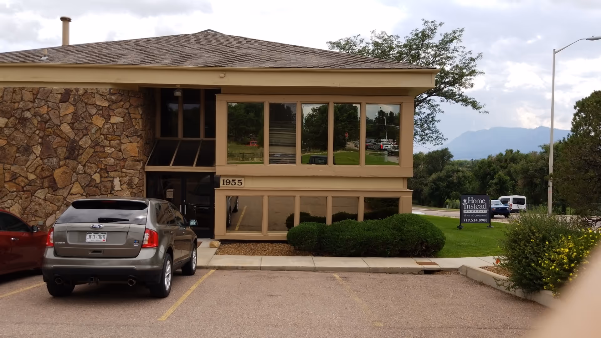 Exterior view of a Home Instead senior care building with stone facade and parking lot.