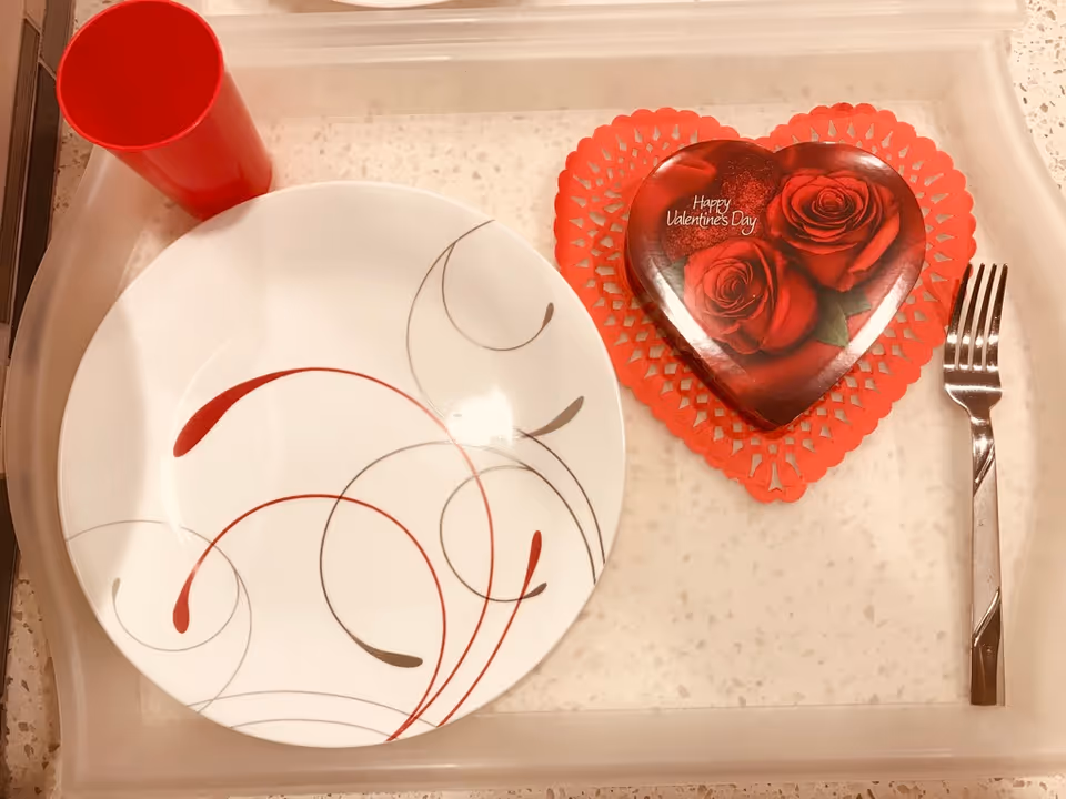 Dining tray with decorative plate, red cup, and heart-shaped Valentine’s Day box.