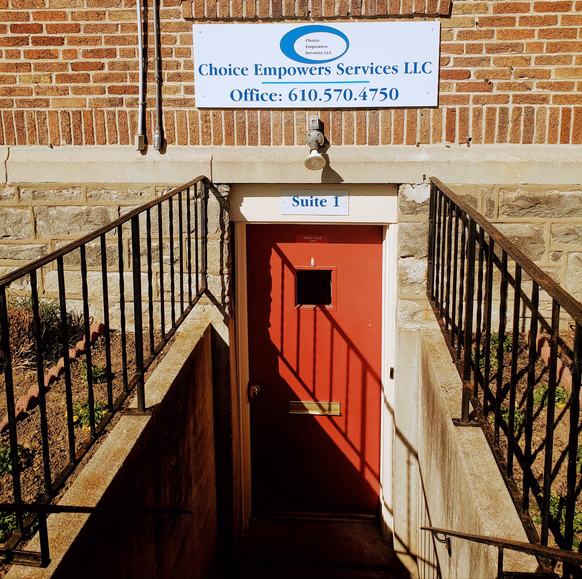 Brick building exterior featuring a red door labeled Suite 1 and a Choice Empowers Services sign.