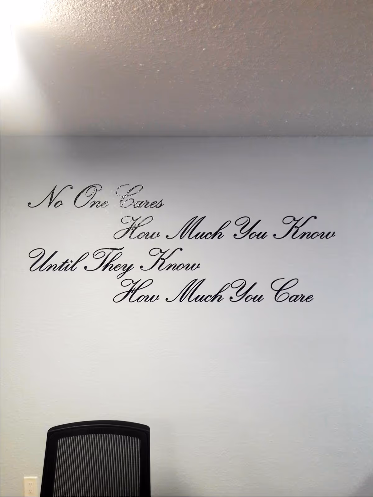 Interior wall with a large scripted quote and a black chair in foreground.