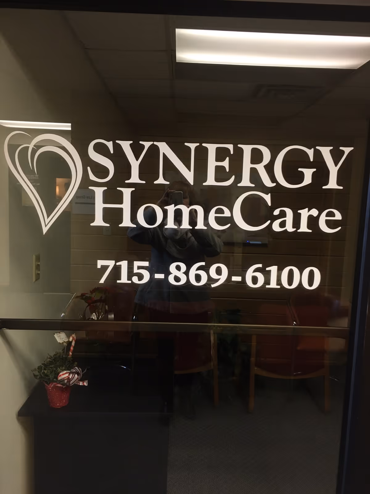 Glass lobby door displays the SYNERGY HomeCare logo and phone number inside.