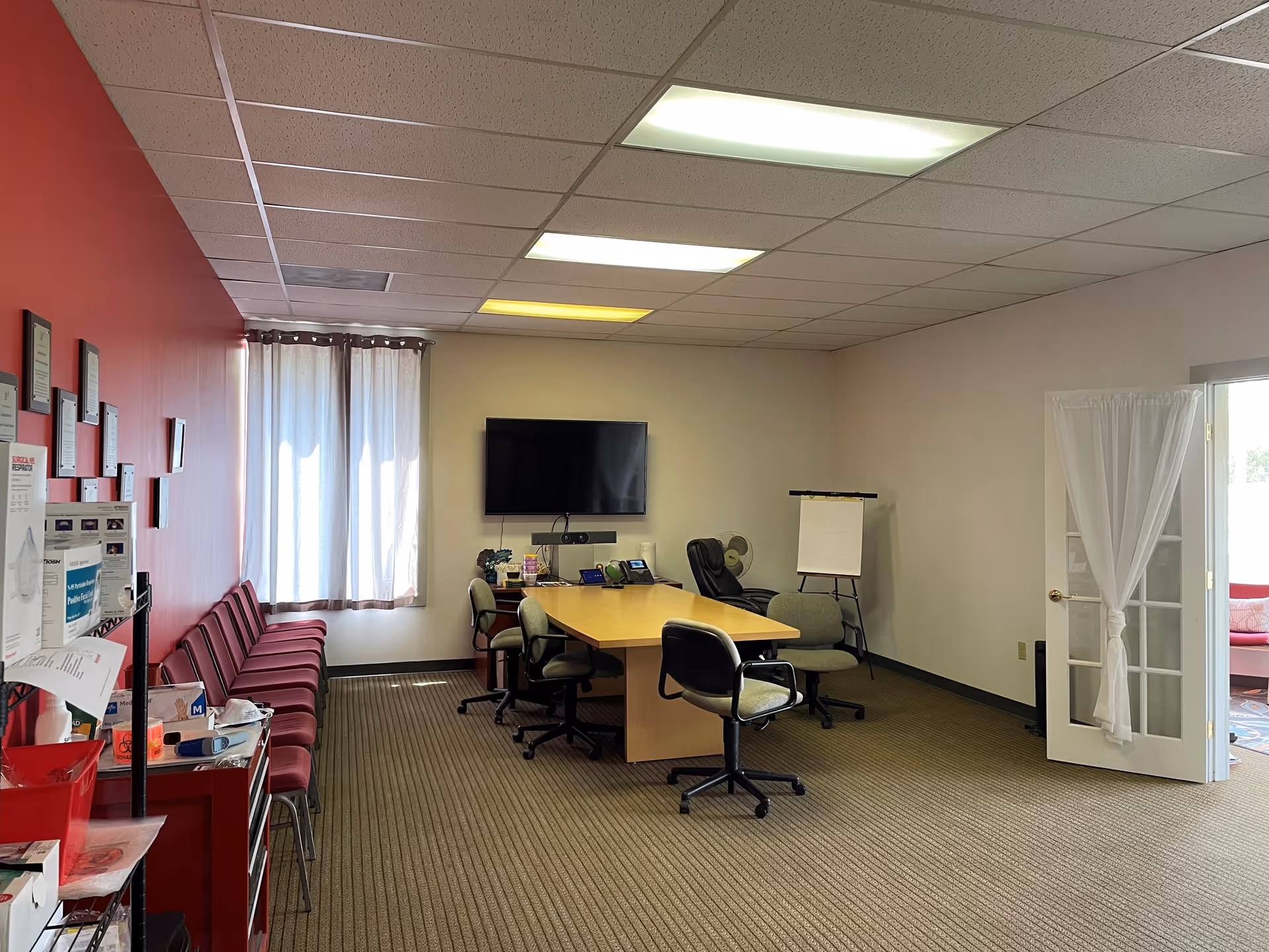 Conference room with a long table, multiple chairs, wall TV, and flip chart.