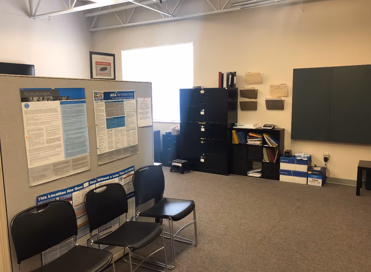 A quiet, office-like room with bulletin boards, cabinets, shelves, and black chairs.