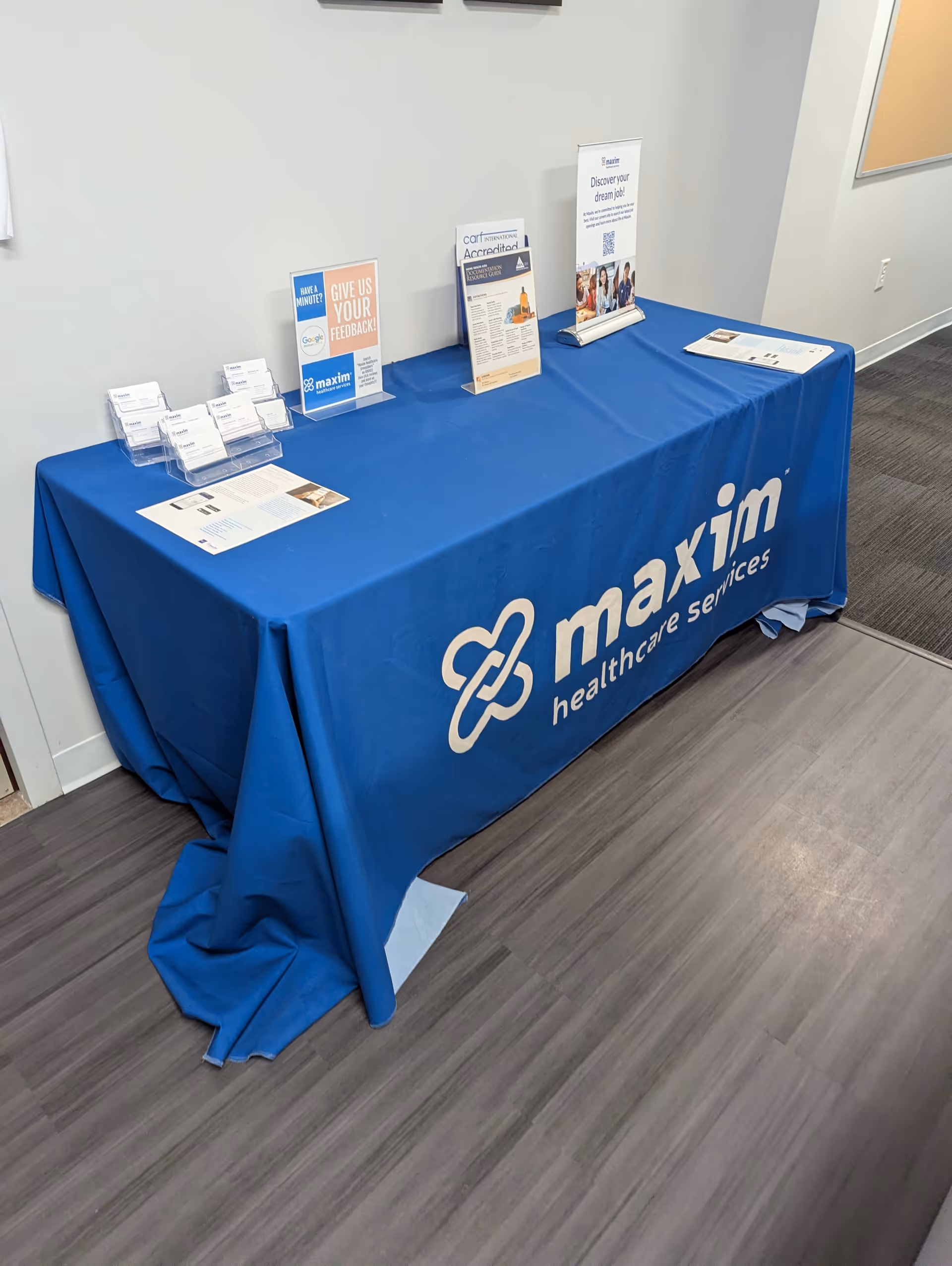 Indoors, blue Maxim Healthcare table with brochures and signage.