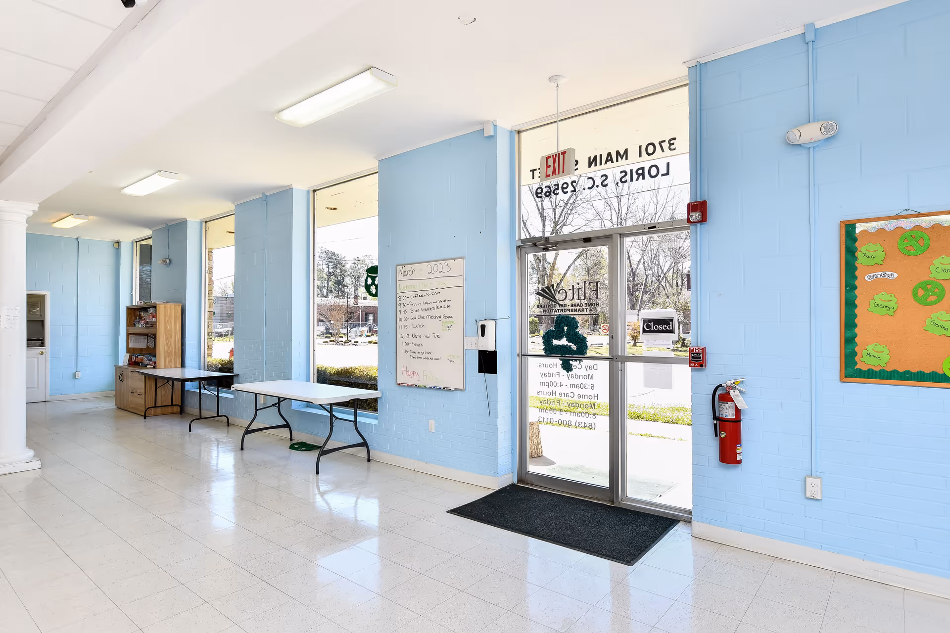 Lobby area at Elite Home Care and Day Centers with walls, glass door, and bulletin boards.