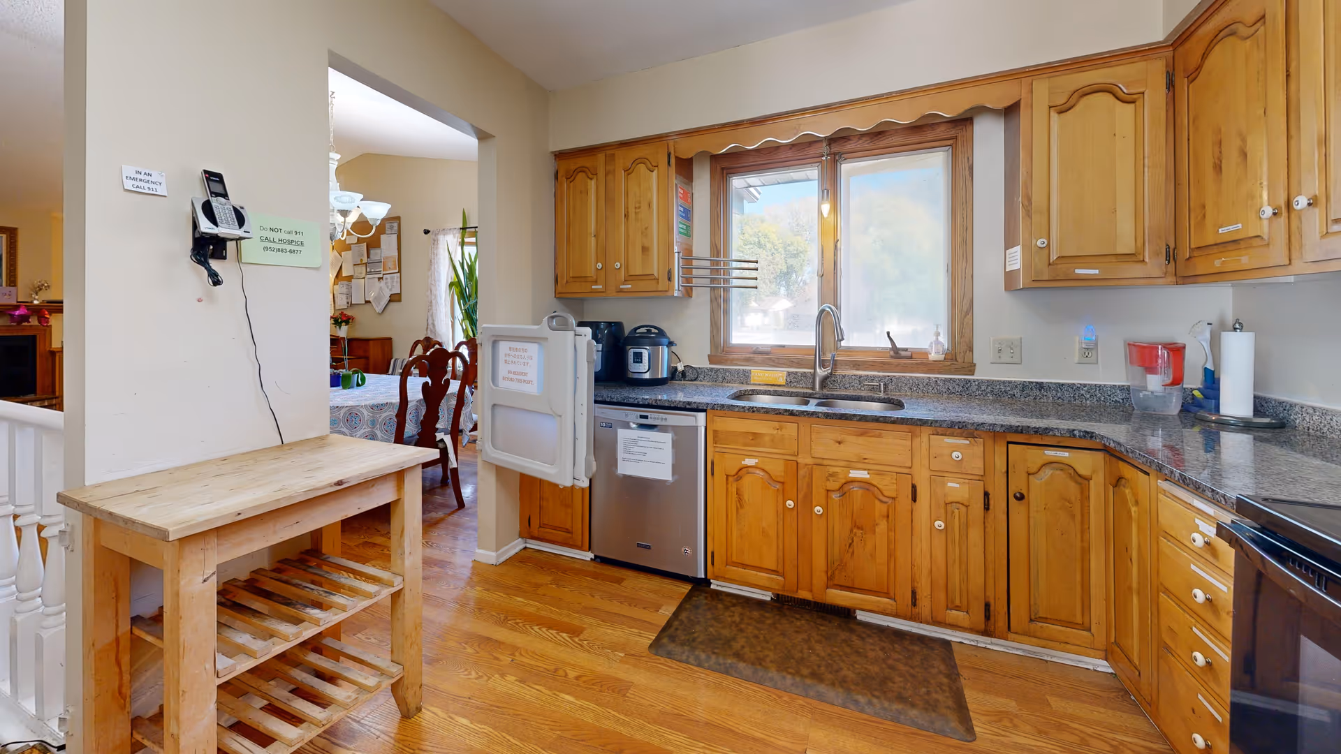 Cozy kitchen with wooden cabinets, granite countertops, double sink, and a window view.
