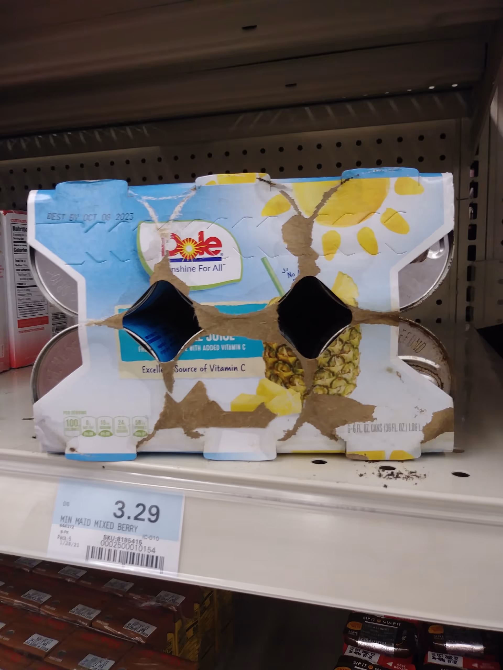 Damaged juice carton on a grocery store shelf with torn cardboard and exposed interior.
