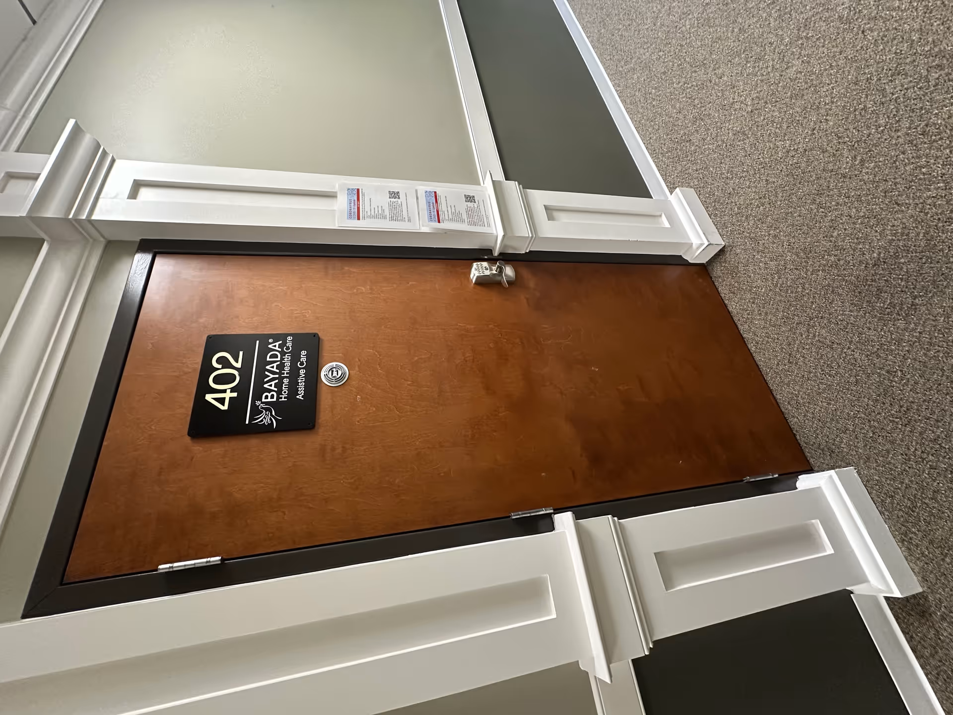 Wooden door labeled 402 in a Bayada Assistive Care hallway.
