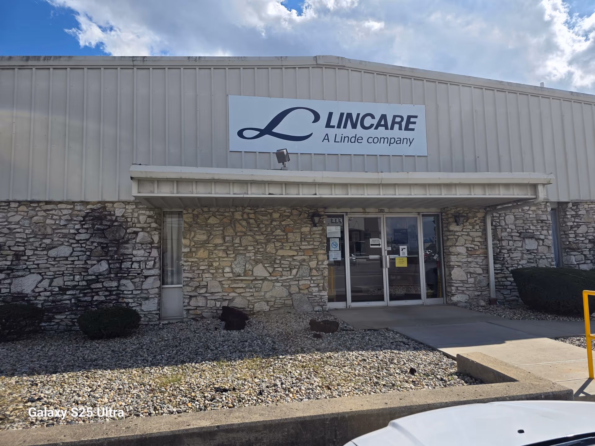 Exterior view of a LINCARE facility entrance with stone facade and glass doors.