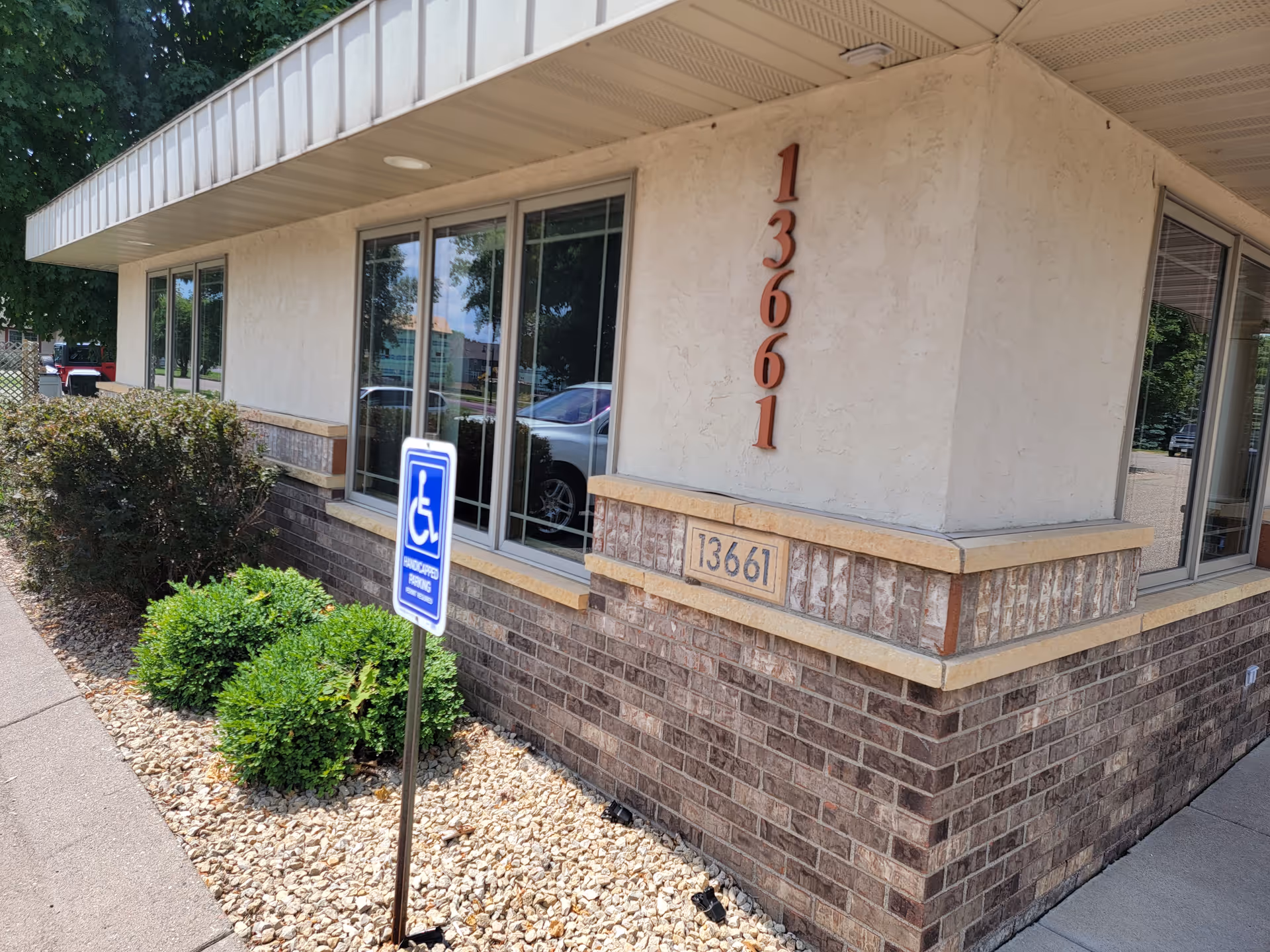 Stone building exterior with large windows, address numbers, and a wheelchair sign.