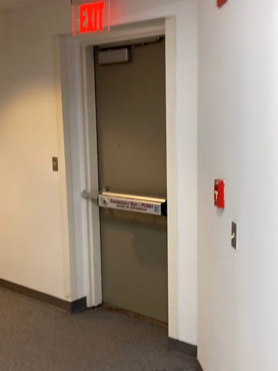 Interior hallway with an exit door, red EXIT sign, and safety equipment.