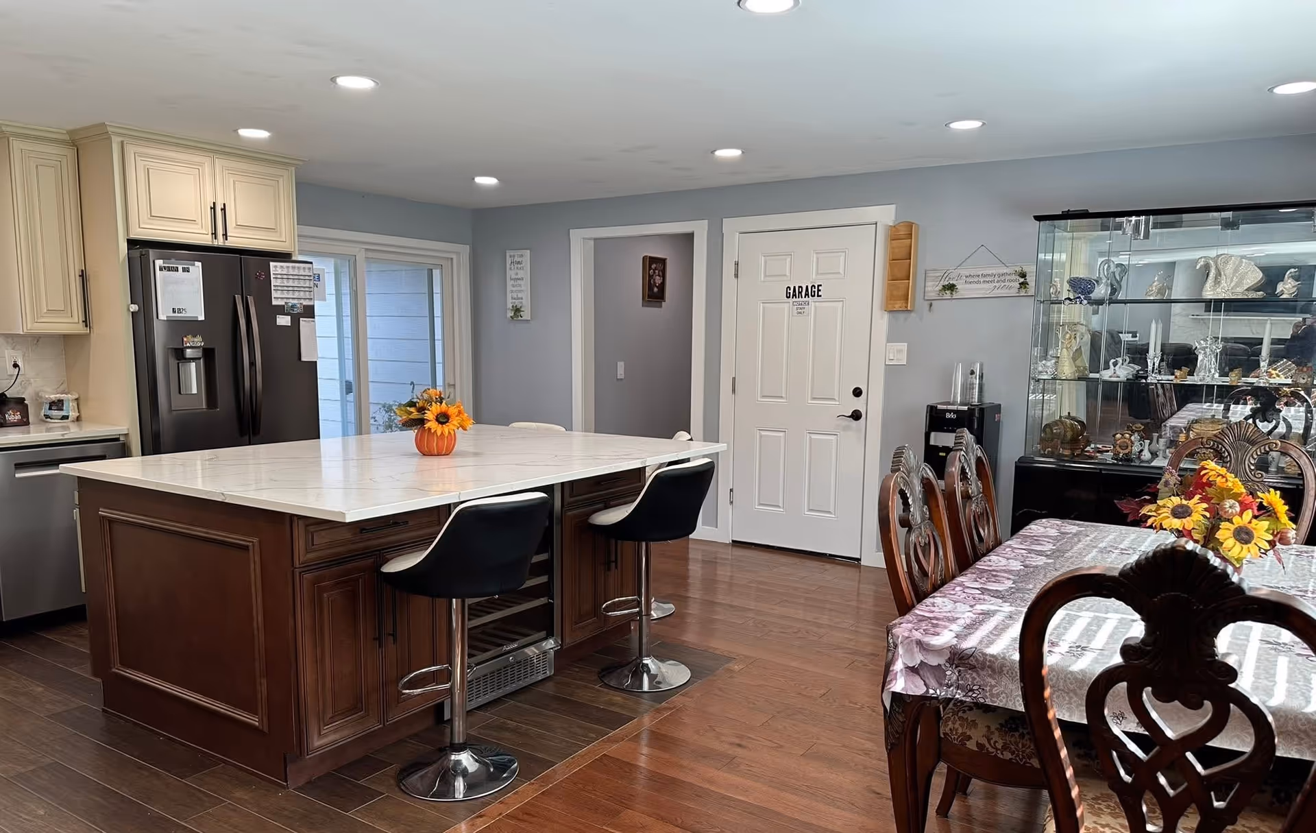 A spacious kitchen area with an island, stools, and a dining table in a residential facility.