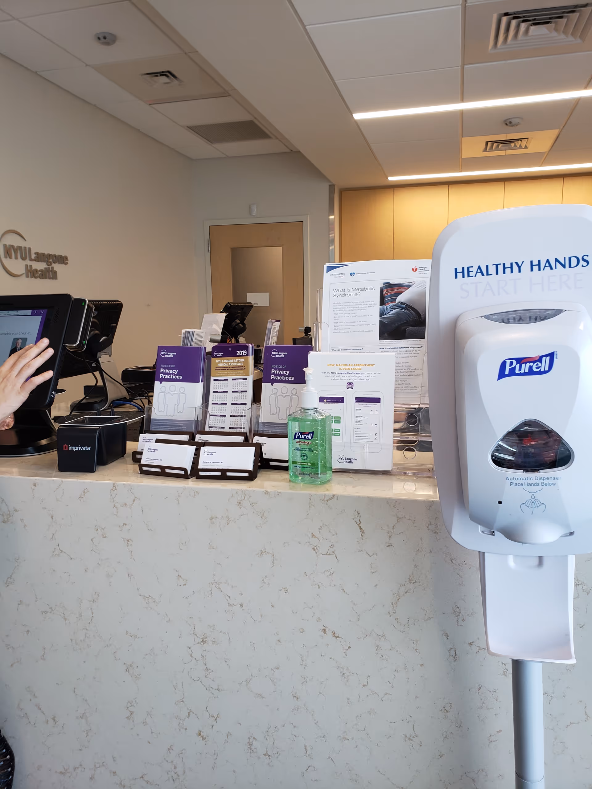 Reception desk with brochures, sanitizer, and NYU Langone Health signage inside an interior clinic.