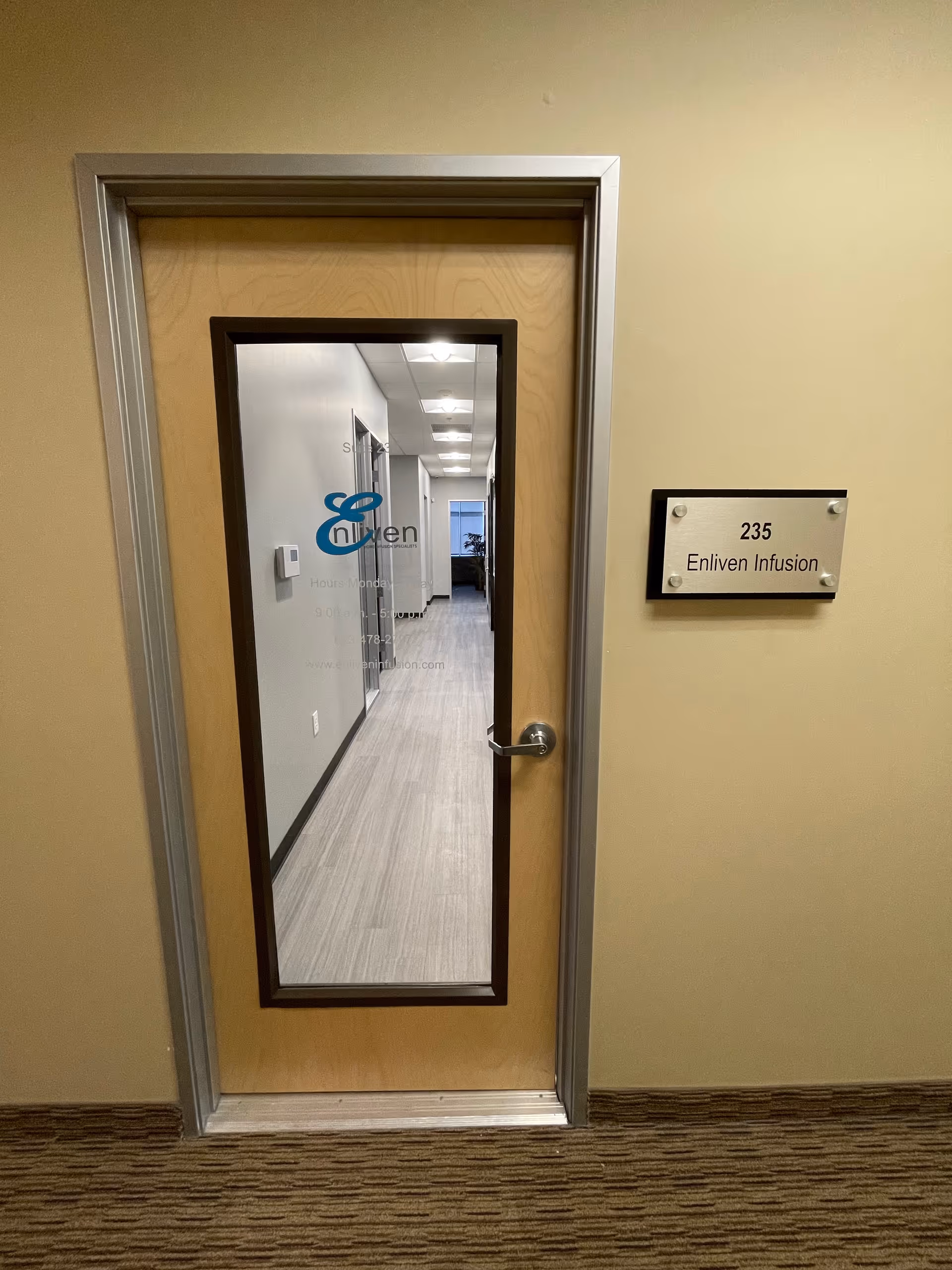 Glass-paneled door opens to a well-lit hallway in a senior care facility.