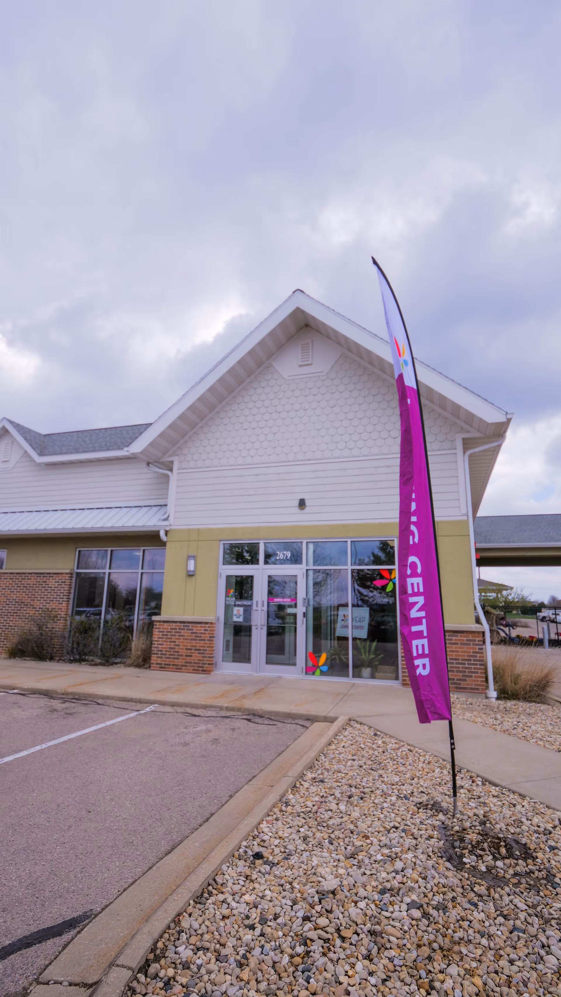 Front view of a light-colored building entrance with a purple promotional flag.